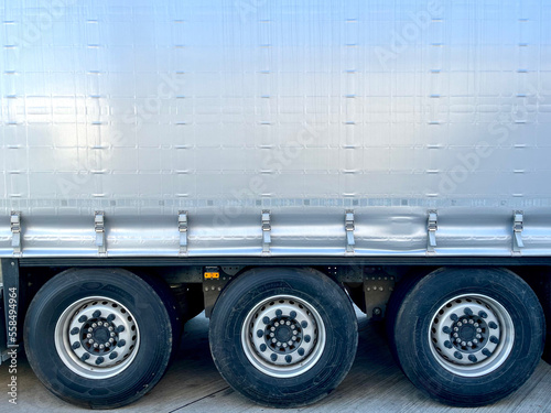 Semi-trailer curtain of gray color for the transportation of a large number of goods. Tent tension lock and three wheels