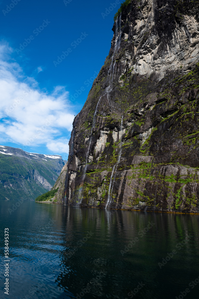 A rainbow reflected in the streams of the waterfall Brudesløret, on the cliffs around Geiranger Fjord, Norway