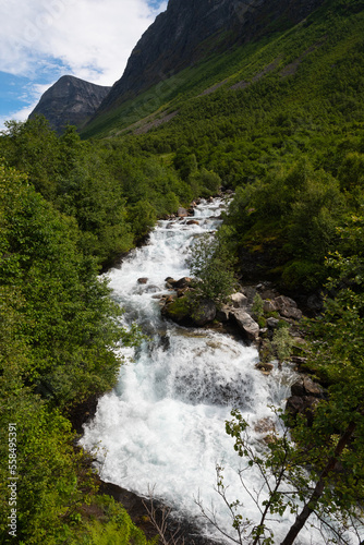 The impressive Storseterfossen  Stors  terfossen  with a path leading behind it throwing water down towards Geiranger  Norway