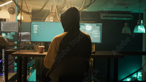 Silhouette of cyber criminal coding encryption to plant malware, looking to steal important information at night. Male spy using computer virus to hack online web network system.