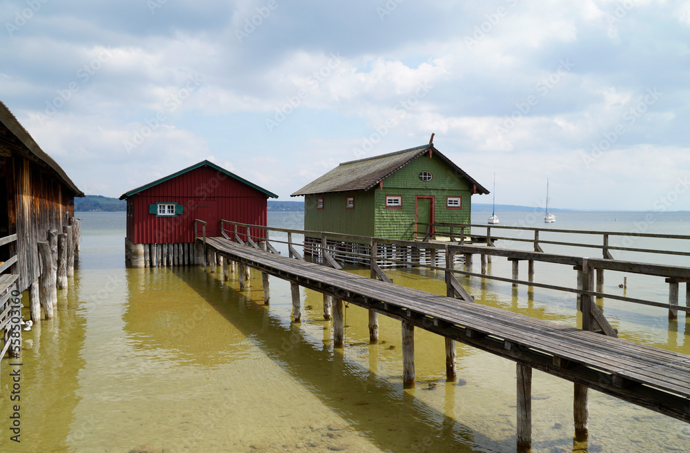 a long wooden pier leading to the colorful boat houses on lake Ammersee in the German fishing village Schondorf (Ammersee, Germany)	
