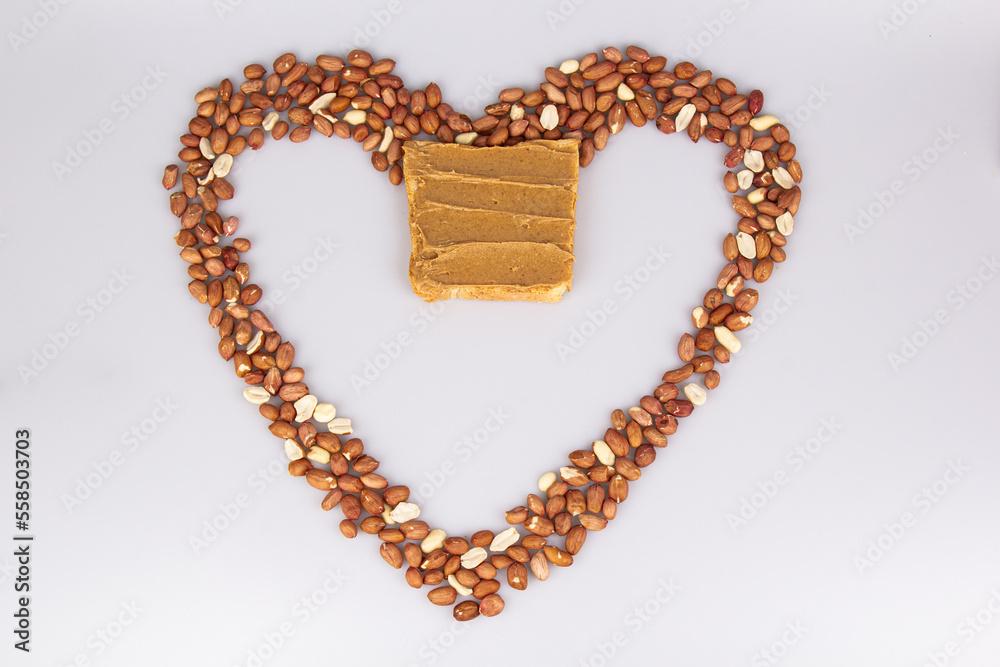 Obraz premium Homemade peanut butter and patterned sandwich isolated on white background. The concept of love for nuts. Favorite breakfast. Nuts in the shape of a heart.