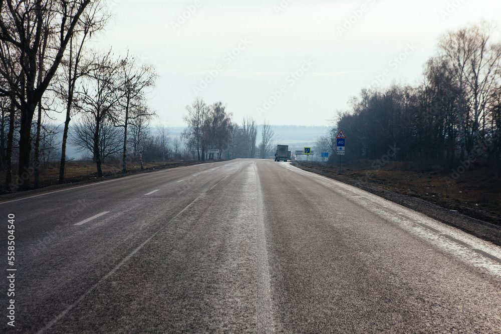 New asphalt road with markings and road signs in the sun's rays