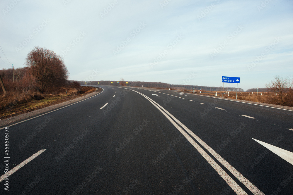 Naklejka premium New asphalt road with markings and road signs in the sun's rays