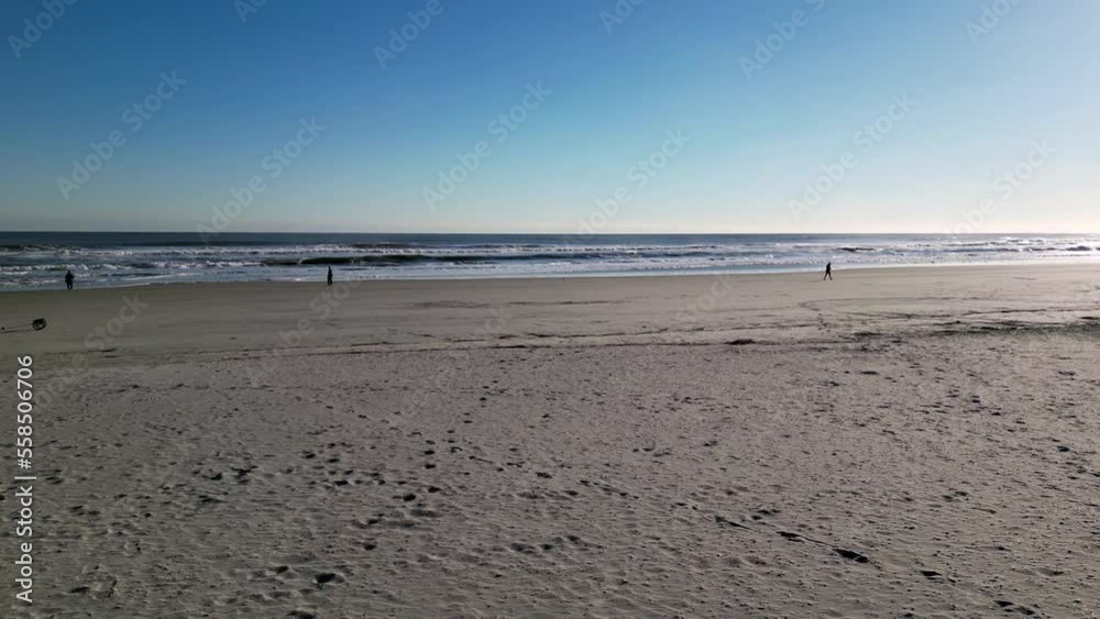 Pan view from a wooden pier right along a wide empty deserted beech on a sunny winter day Pan view from a wooden pier right along a wide empty deserted beech on a sunny winter day