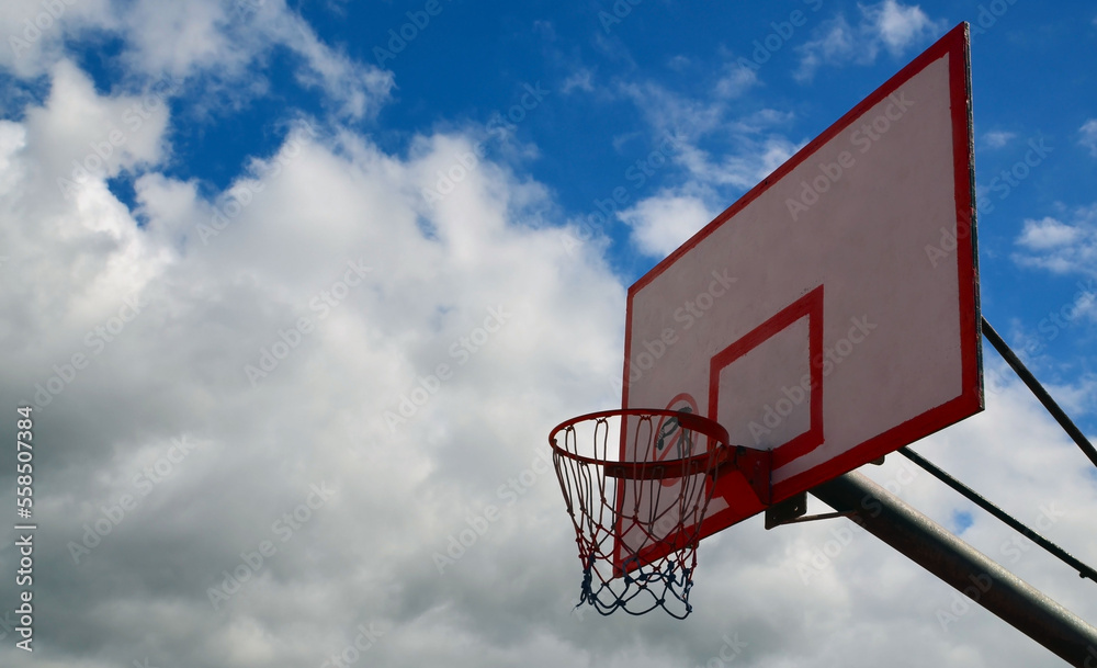 Basketball hoop on blue sky background. Outdoors recreational sport equipment on streetball field. Selective focus.