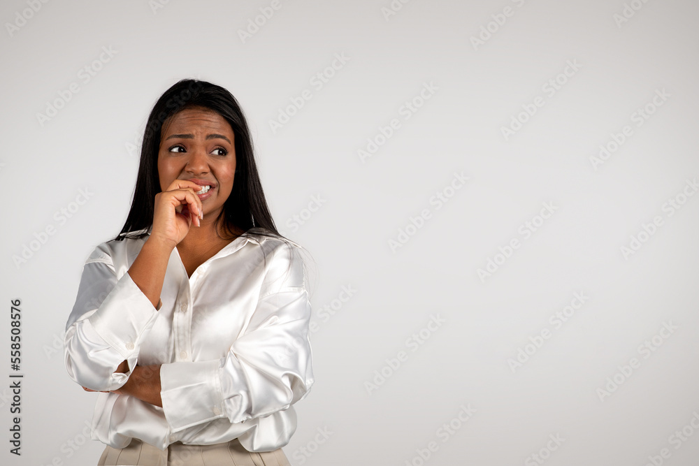 Sad confused young african american business woman biting her finger, suffering from pressure, stress Sad confused young african american business woman biting her finger, suffering from pressure, stress