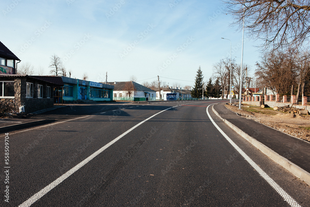 Fototapeta premium New asphalt road with markings and road signs in the sun's rays