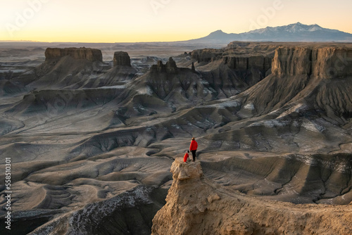 Woman with dog looking at view in desert during sunset photo