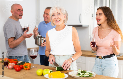 Happy family with elderly parents preparing lunch in a modern kitchen