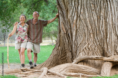 A mature couple poses against a giant Fremont cottonwood tree (Populus fremontii) in Zion National Park, Utah. photo