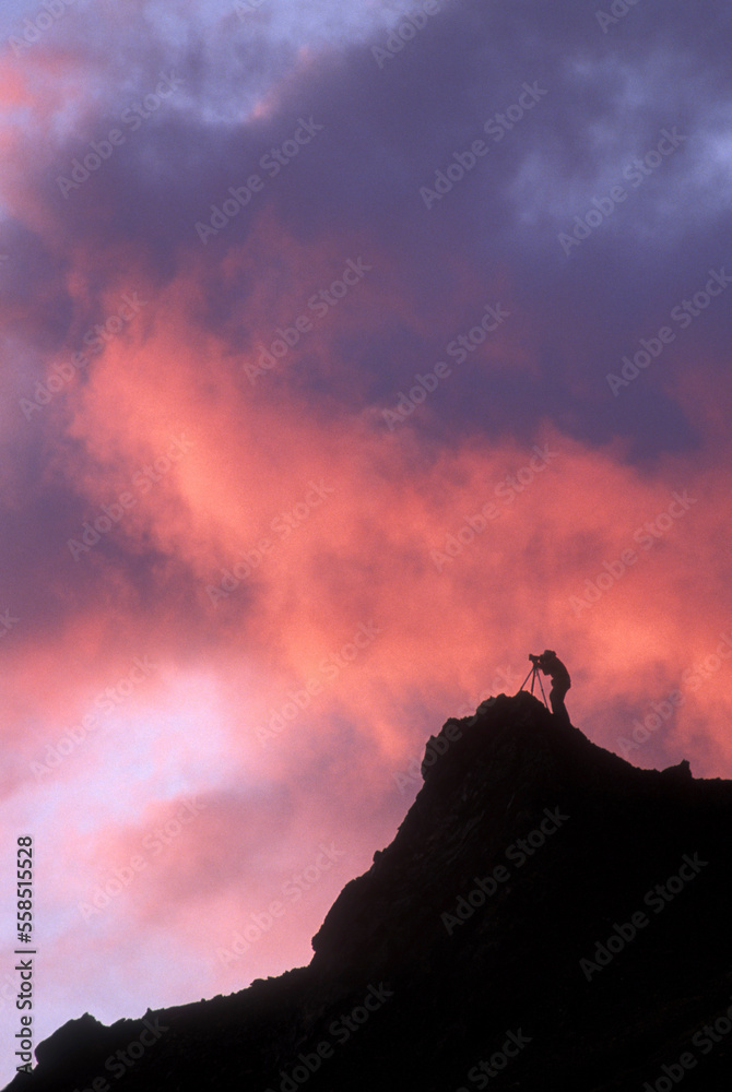 USA, Alaska, Denali National Park, (MR) Photographer stands with tripod on cliffs above Polychrome Pass at sunset USA, Alaska, Denali National Park, (MR) Photographer stands with tripod on cliffs above Polychrome Pass at sunset