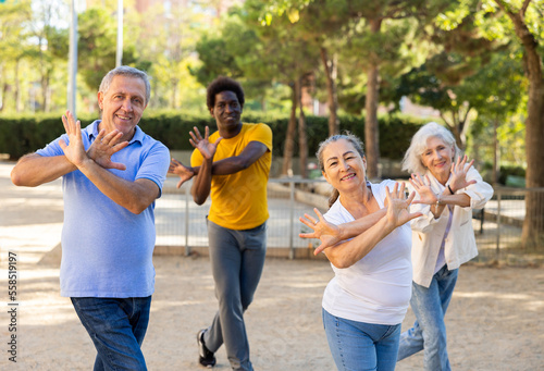 Group of multiracial friends, various ages getting together outdoors and dancing simple moves on a sunny day in autumn