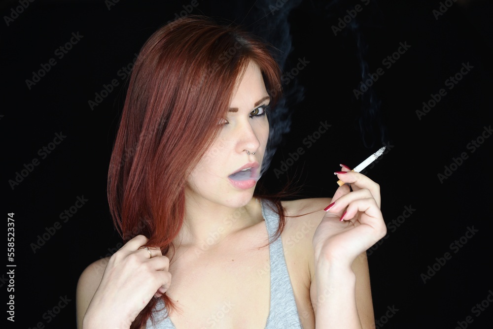 Young girl smokes a cigarette isolated against a black background Young girl smokes a cigarette isolated against a black background