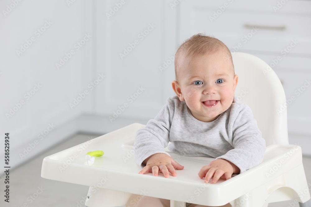 Cute little baby in high chair at home