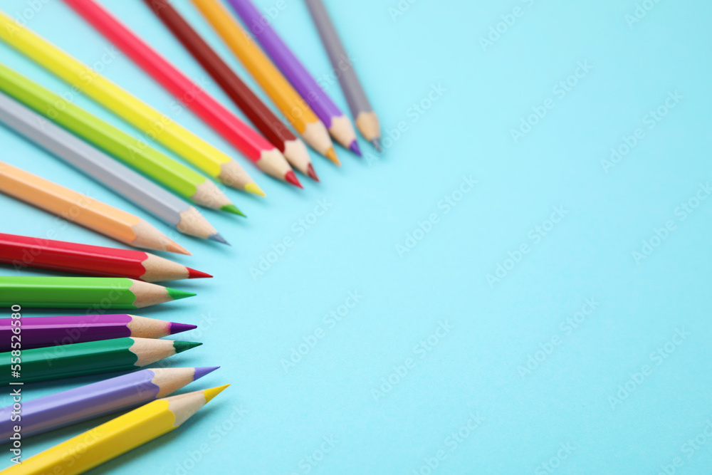 Colorful wooden pencils on light blue background, above view. Space for text