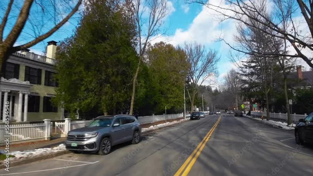 Driving POV snowy Vermont neighbourhood street with white wooden residential houses and winter trees Driving POV snowy Vermont neighbourhood street with white wooden residential houses and winter trees