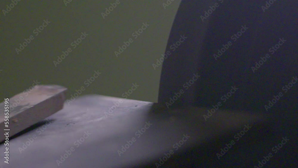 Slow motion shot of sparks flying off of a chisel being sharpened on a grindstone