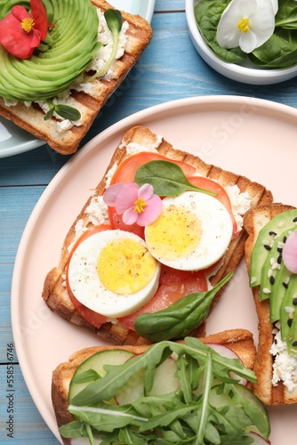 Different delicious sandwiches on light blue wooden table, flat lay