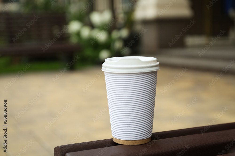 Paper cup of coffee on wooden bench outdoors. Takeaway drink Paper cup of coffee on wooden bench outdoors. Takeaway drink