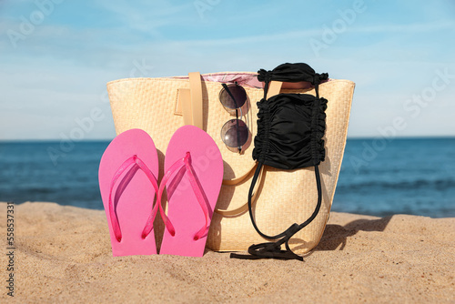 Summer bag with beach accessories on sand near sea
