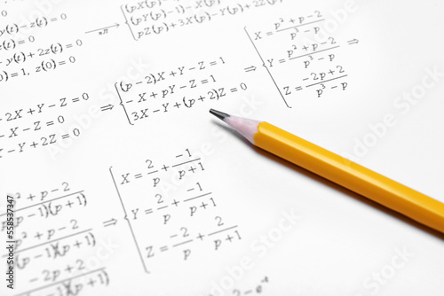 Sheet of paper with mathematical formulas and pencil, closeup