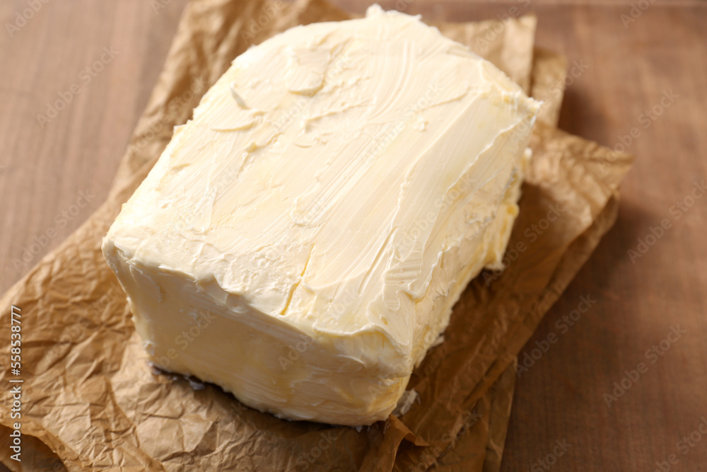 Parchment with tasty homemade butter on wooden table