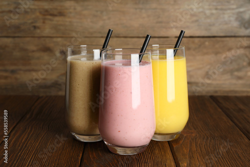 Glasses with different smoothies on wooden table