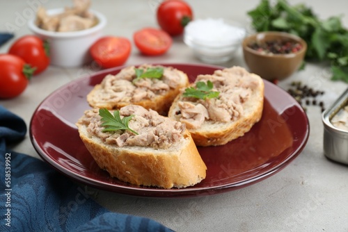 Tasty sandwiches with cod liver and different products on light grey table