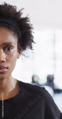Vertical video half face portrait of smiling african american woman at a gym, with copy space photo