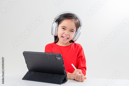 little girl asia cute put on headphones have video call distant class with teacher using laptop,  study online on computer, homeschooling concept