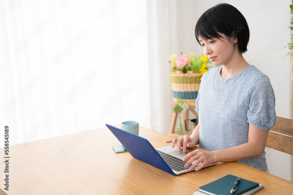 家でノートパソコンを操作する若い女性
