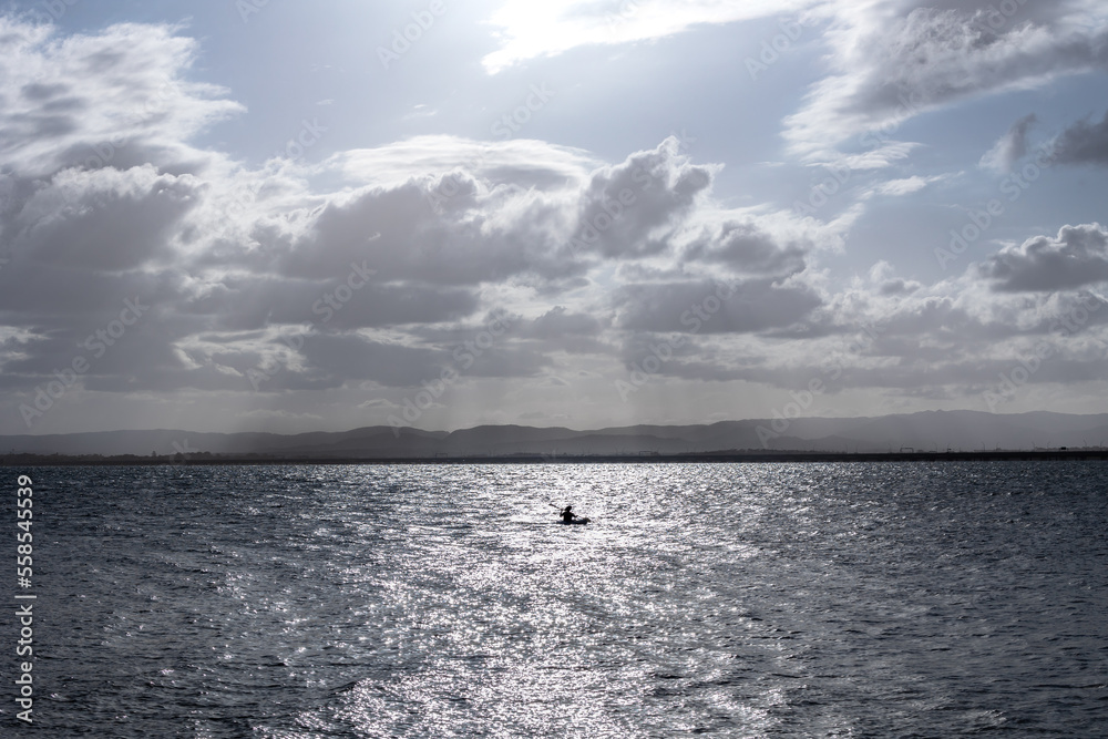 a man kayaking with clouds over the sea 
