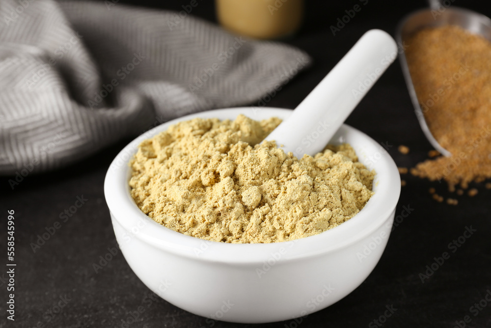 Mortar with mustard powder on black table, closeup Mortar with mustard powder on black table, closeup