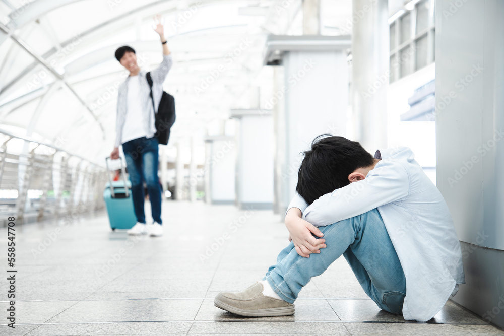 Asian boy sits crying on the skywalk connecting the walkway to the ...