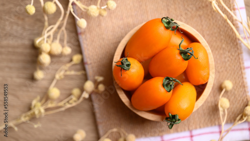 Orange cherry tomatoes in wooden bowl, fresh organic vegetable