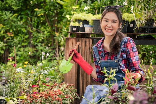 Beautiful Asian woman gardener working inside the propagation table at plant nursery garden center and holding planting spoon in ornaments shop. Farmer and agriculture concept © krumanop