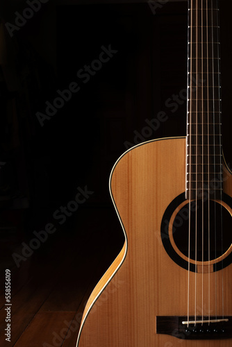 Classic Acoustic guitar close up, dramatically lit on a black background with copy space