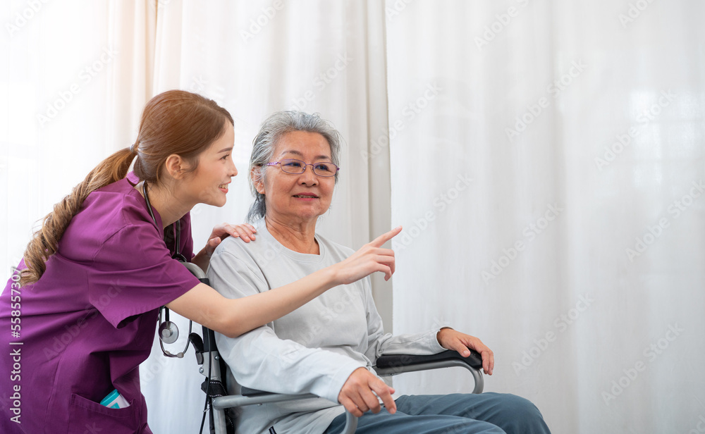 Asian young nurse taking care and talking mature female patient sitting on wheelchair in hospital. Healthcare concept, Banner cover design.