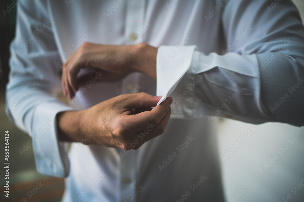 Man tying cufflinks in white shirt Man tying cufflinks in white shirt