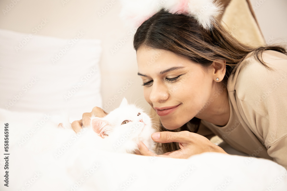 Portrait of the beautiful little girl with brunette loose hair the hugging her white cat. Girl is laying with her cat. Young woman with her lovely white cat Portrait of the beautiful little girl with brunette loose hair the hugging her white cat. Girl is laying with her cat. Young woman with her lovely white cat