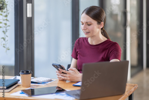 Portrait of Young canada american business woman using a mobile phone and works on a laptop computer in the modern home workplace office