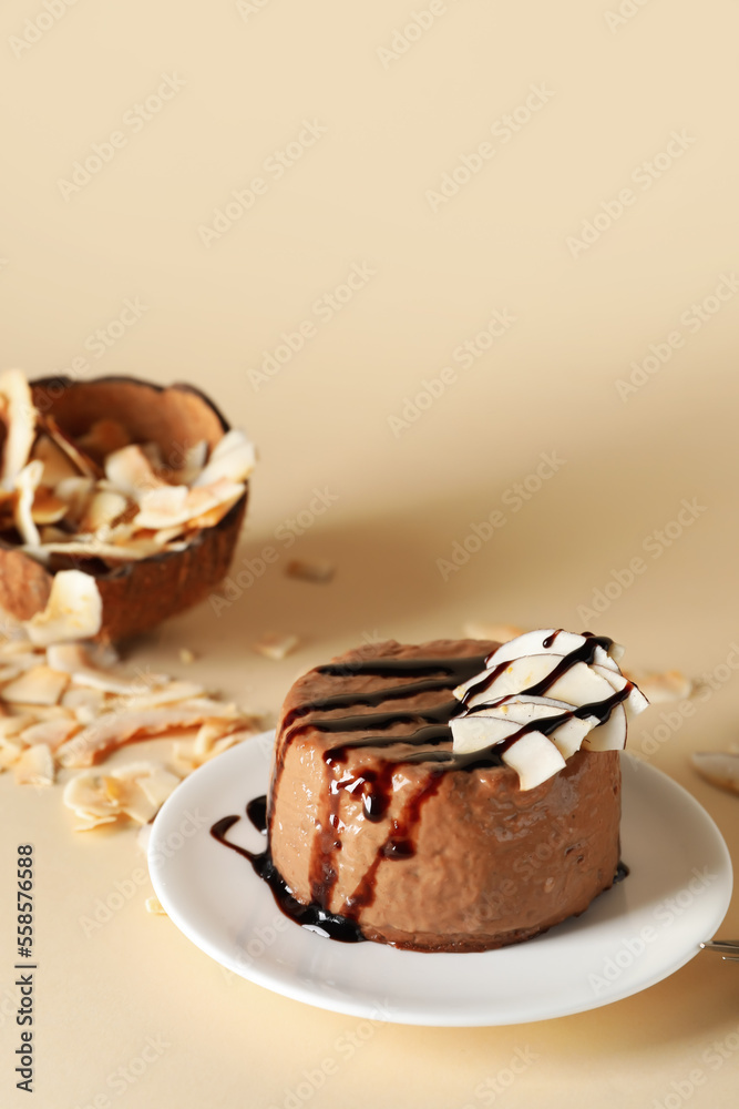 Plate with delicious pudding, chocolate sauce and coconut on beige background Plate with delicious pudding, chocolate sauce and coconut on beige background