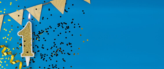 Number 1 gold celebration candle on star and glitter blue background. Copy space.