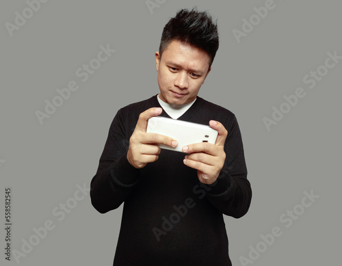 Handsome man playing game on cell phone isolated on plain background