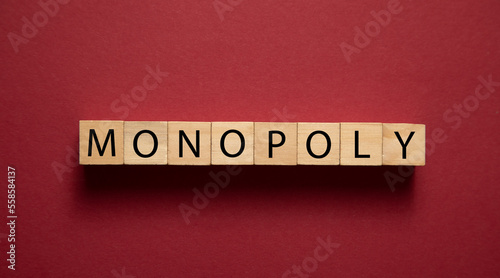 Word Monopoly on wooden cubes on the bordeaux background.