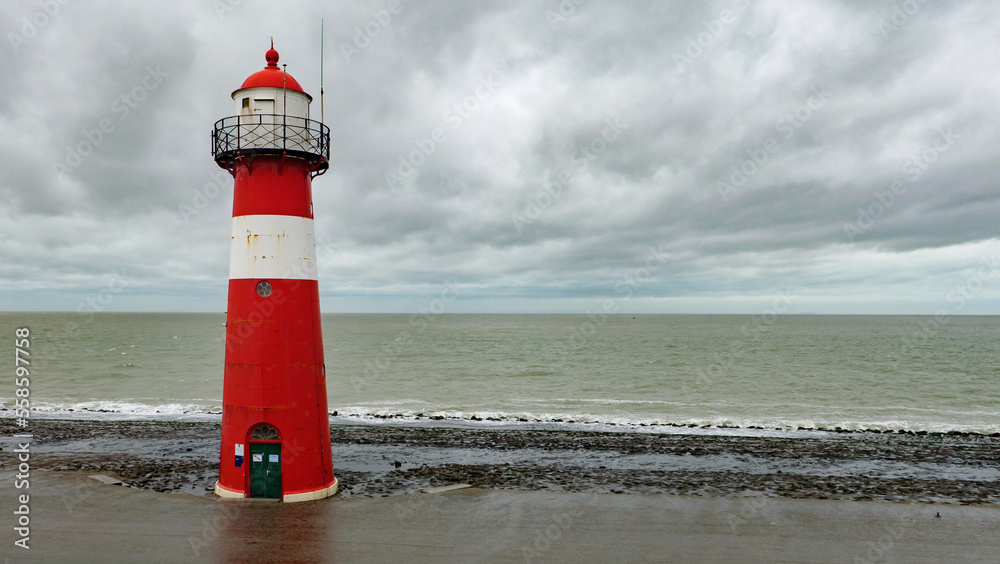 Red and white lighthouse by the sea in westkapelle, walcheren, netherlands, in winter