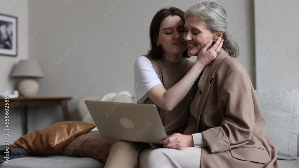 adult daughter showing elderly mother travel photos using laptop adult daughter showing elderly mother travel photos using laptop