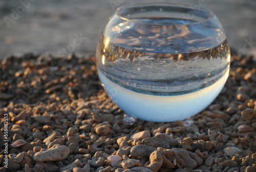 Sea and sundown reflection in a glass bowl on a beach