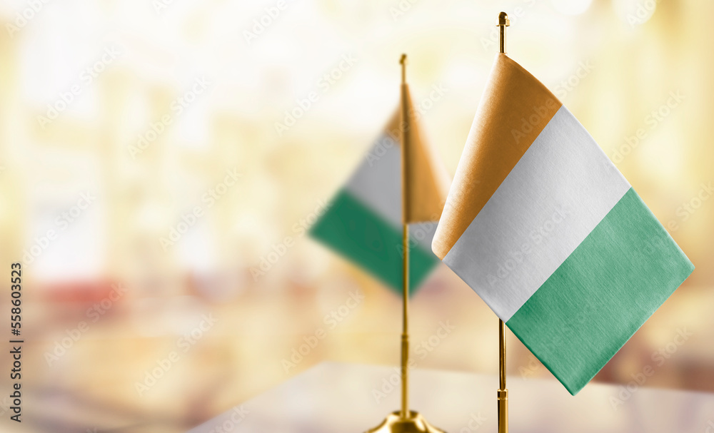 Small flags of the Cote dIvoire on an abstract blurry background - obrazy, fototapety, plakaty 